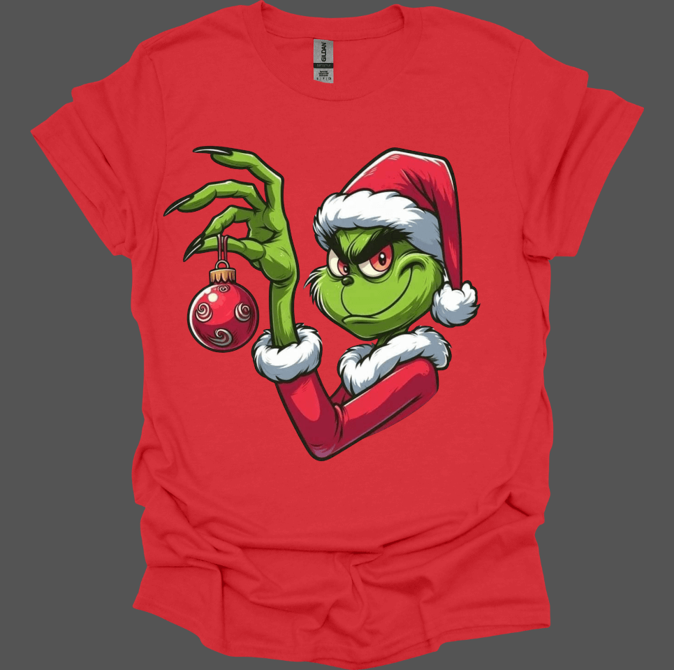 Red Christmas With the Grinch Tee with a graphic of a green character holding a Christmas ornament on a gray background