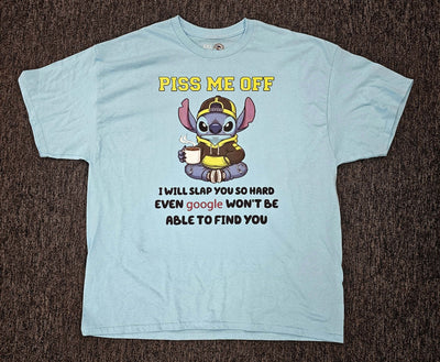 Light blue t-shirt with cartoon character and text on a dark brown surface